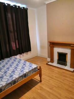 A simple double bedroom featuring a bed, wooden...