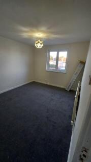 A well-lit, clean bedroom with a single window ...