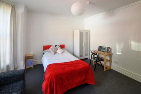 A cozy single bedroom featuring a neatly made b...