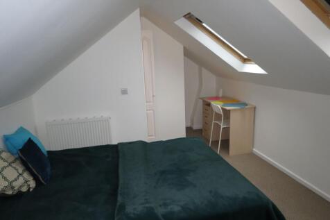Bright and cozy bedroom featuring a large bed w...