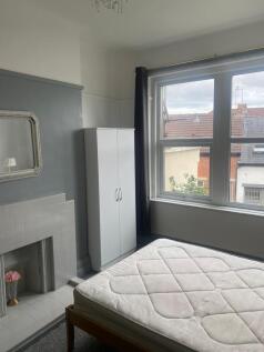 A cozy single bedroom featuring a large window ...