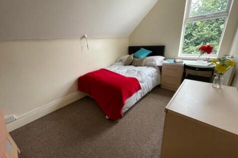A cozy bedroom featuring a single bed draped wi...