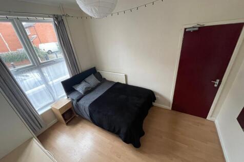 A cozy bedroom featuring a double bed with dark...