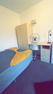A cozy student bedroom featuring a single bed w...