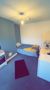 A cozy bedroom featuring a single bed with a sm...