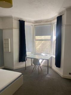 A bright and airy bedroom featuring a large bay...
