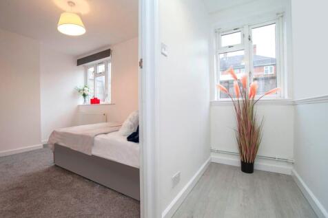 A clean and well-lit double bedroom with a cozy...