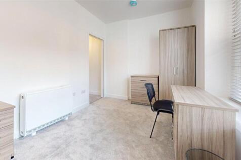 Bright and clean bedroom featuring a desk, ward...