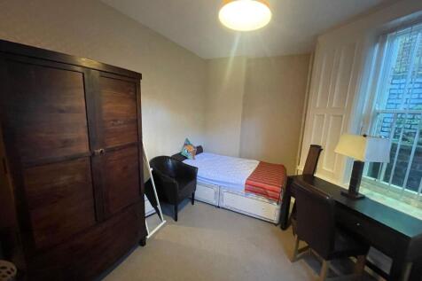 A cozy single bedroom featuring a bed, a dark w...