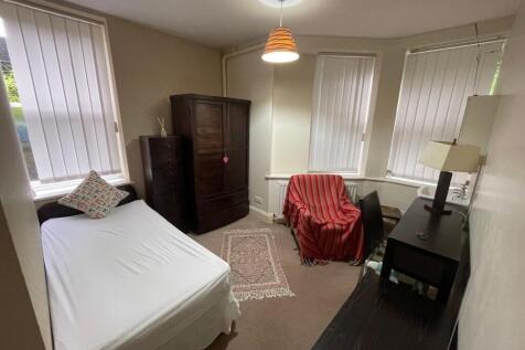 A cozy bedroom featuring a single bed with a de...