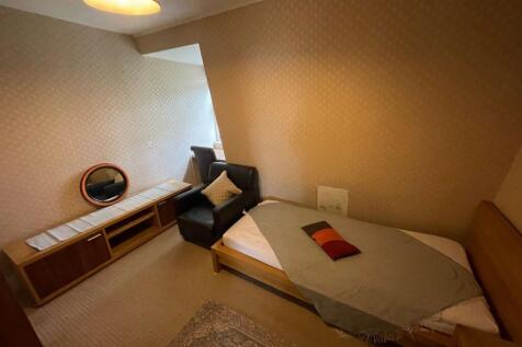 A cozy single bedroom featuring a neatly made b...
