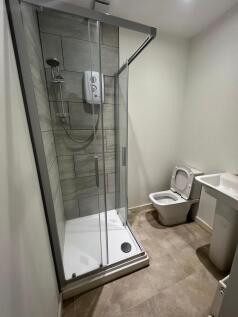 A modern bathroom featuring a glass-enclosed sh...