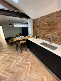 Modern kitchen featuring sleek black cabinetry,...