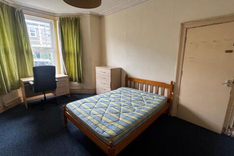 A modest bedroom featuring a single bed with a ...