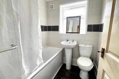 A clean and tidy bathroom featuring a bathtub, ...