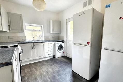 A well-lit, modern kitchen featuring white cabi...