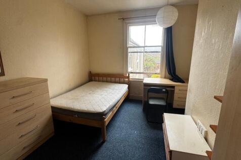 A cozy student bedroom featuring a single bed, ...