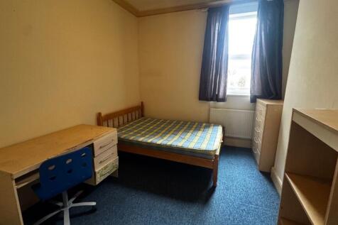 A modest bedroom featuring a single bed with a ...
