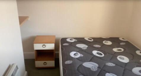 A cozy bedroom featuring a neatly made bed with...