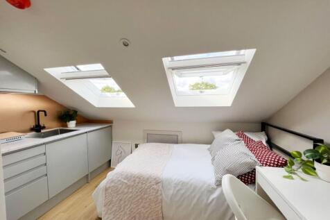 Bright and cozy attic bedroom featuring two sky...
