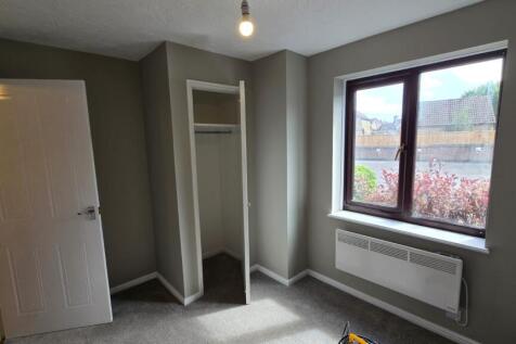 A bright and tidy bedroom featuring a large win...