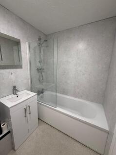 Modern bathroom featuring a sleek white bathtub...