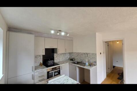 Modern kitchen featuring white cabinetry, a mar...