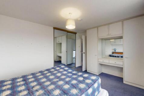 A clean, well-lit bedroom with a comfortable be...