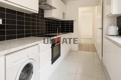 Modern kitchen with sleek white cabinetry, blac...