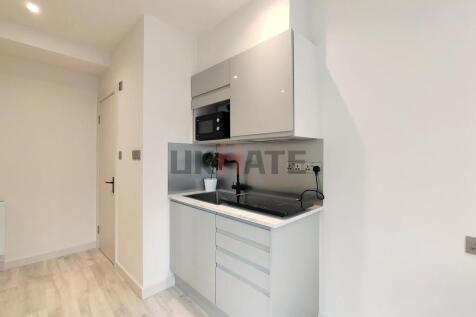 A modern compact kitchen with sleek white cabin...