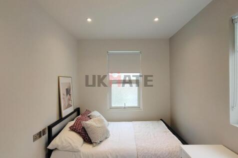 A bright and tidy bedroom featuring a neatly ma...