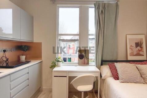 A cozy single bedroom featuring a bed with stri...