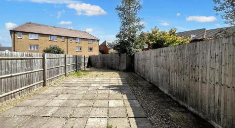 A long, paved garden area bordered by wooden fe...