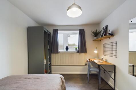 A bright and clean bedroom featuring a neatly m...