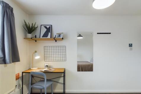 A bright and tidy bedroom featuring a cozy work...