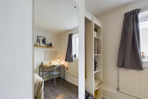 A cozy bedroom featuring a single bed near a wi...