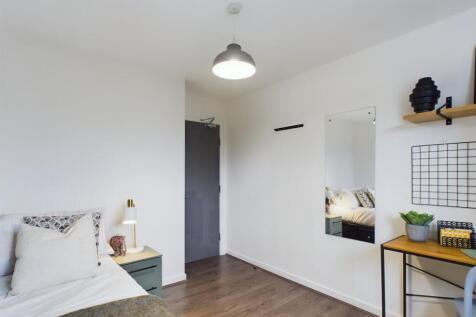 A bright and tidy bedroom featuring a comfortab...