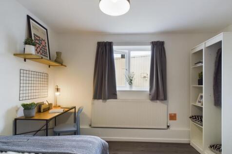 A bright and tidy bedroom featuring a comfortab...