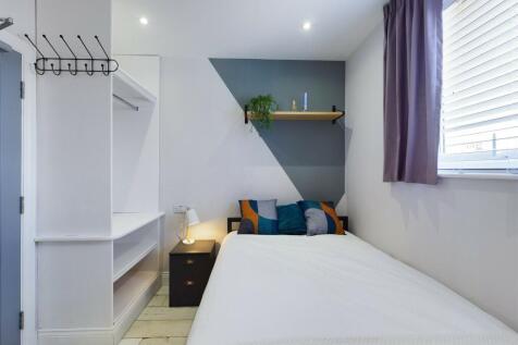 A bright and clean single bedroom featuring a c...