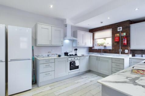 Bright and modern kitchen with white cabinetry,...