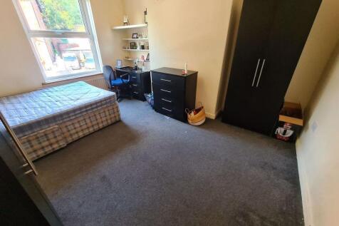 A modest student bedroom featuring a single bed...