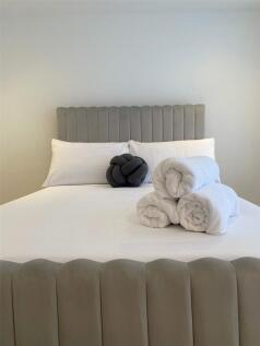 A spacious and neatly made master bedroom featu...