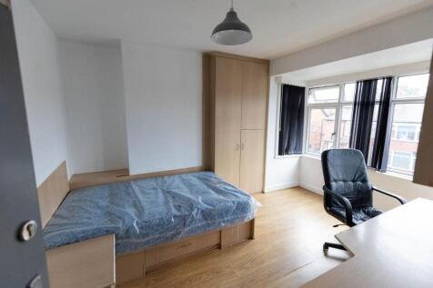 A bright single bedroom featuring a bed with a ...