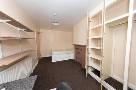 A modest bedroom featuring shelves, a radiator,...
