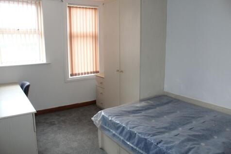 A simple, basic bedroom featuring a window with...