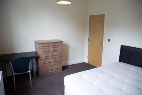 A well-maintained bedroom featuring a bed with ...