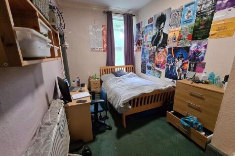 A cozy single bedroom with a comfortable wooden...