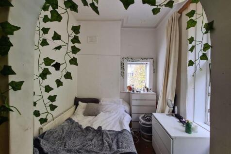 A cozy single bedroom featuring a neatly made b...
