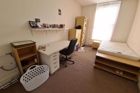 A simple, well-lit student bedroom featuring a ...