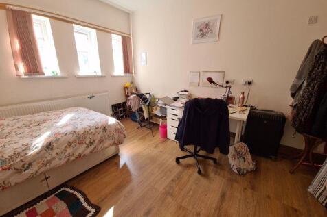A cozy single bedroom with a large window allow...